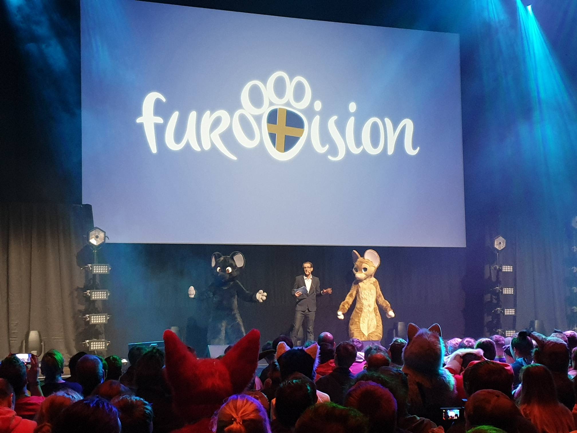 Dalziel on stage as the presenter, with convention mascots Mausie and Iris.